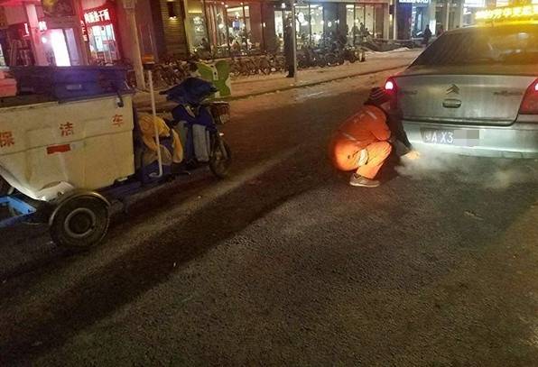 環衛工蹲在出租車排氣管旁暖手，畫麵讓人心疼